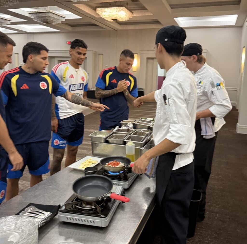 Two culinary students serving four soccer players in a buffet line